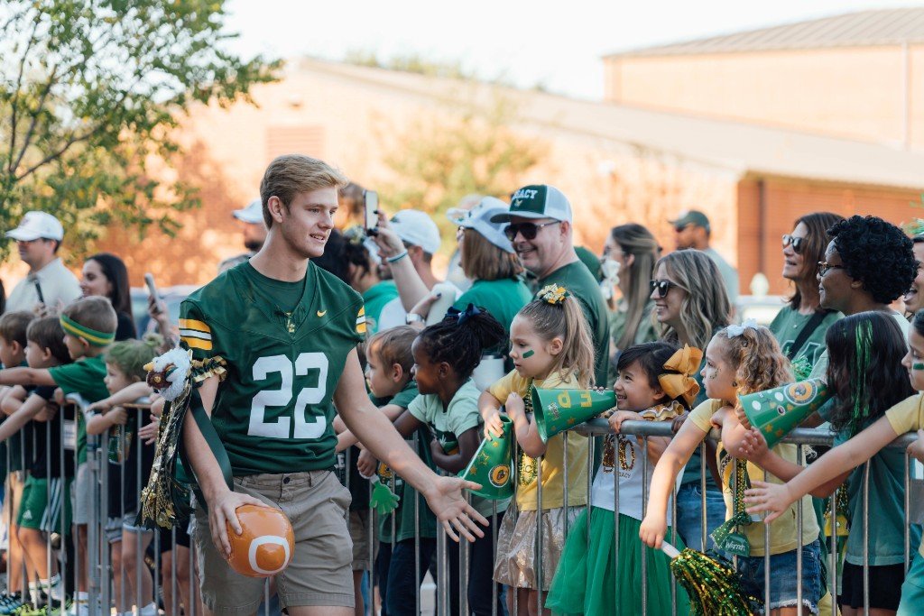 Students walking in the Homecoming parade with homecoming mums