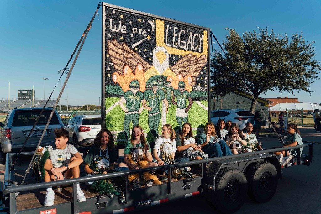 Students wearing green and gold homecoming mums in the parade