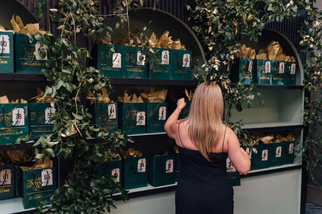 Guest selecting a numbered Mystery Bag from a vine-draped display
