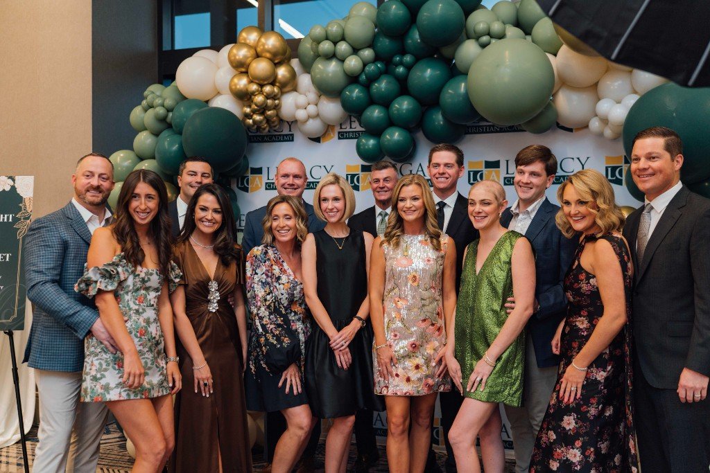 Guests posing under a green and gold balloon arch at Legacy Night