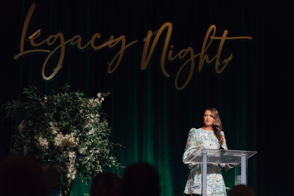 Speaker at the Legacy Night podium beneath the gold Legacy Night sign