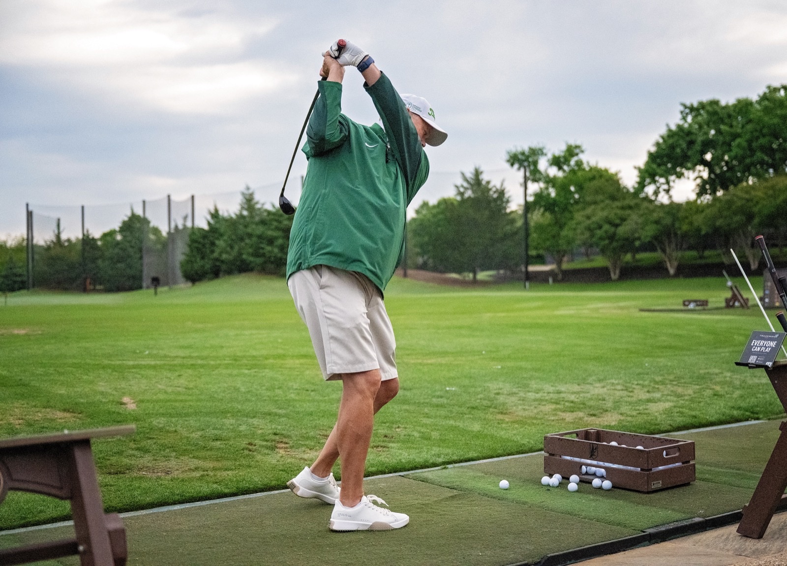 Golfer mid-swing at the driving range